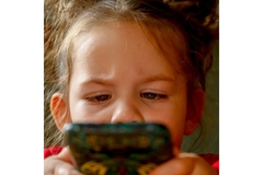 Image Little girl looking suspicious while holding a phone
